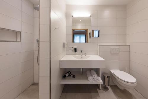a white bathroom with a sink and a toilet at ArlBerglife Ferienresort in Pettneu am Arlberg