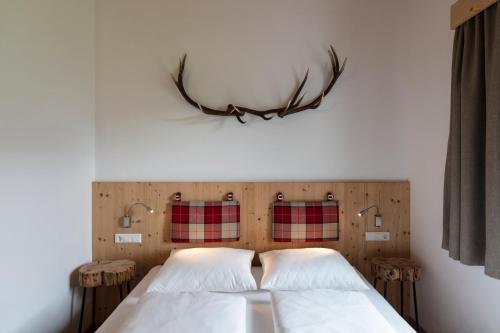 a bedroom with two beds with antlers on the wall at ArlBerglife Ferienresort in Pettneu am Arlberg