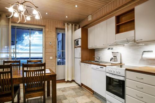 a kitchen with a table and a dining room at Levin Alppitalot Alpine Chalets Deluxe in Levi