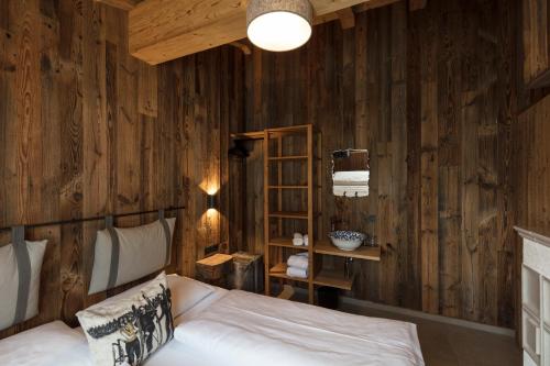 a bedroom with wooden walls with a bed and a shelf at ArlBerglife Ferienresort in Pettneu am Arlberg