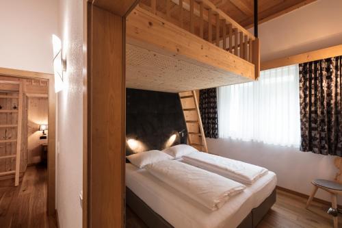 a bedroom with a bunk bed with white sheets at ArlBerglife Ferienresort in Pettneu am Arlberg