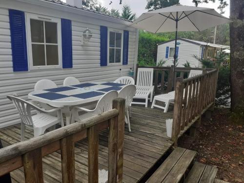 a deck with a table and chairs and an umbrella at Mobil-home "Le pin bleu" à St-Paul-les-Dax in Mées