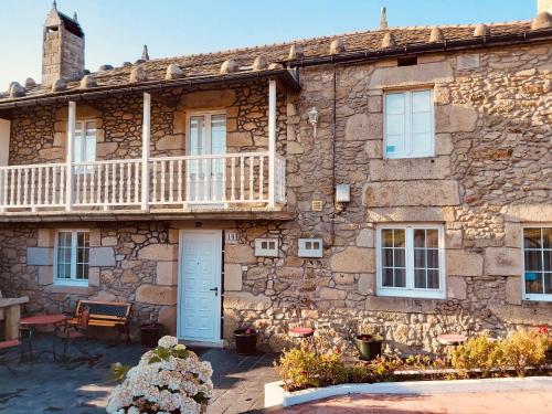 an old stone house with a porch and a balcony at Casa Pereiro playa de Esteiro in Viveiro