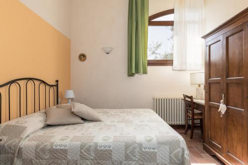 a bedroom with a bed and a desk and a window at Vernaccia Country house in Tavarnelle in Val di Pesa