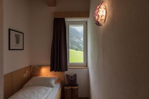 a bedroom with a bed and a window at ArlBerglife Ferienresort in Pettneu am Arlberg