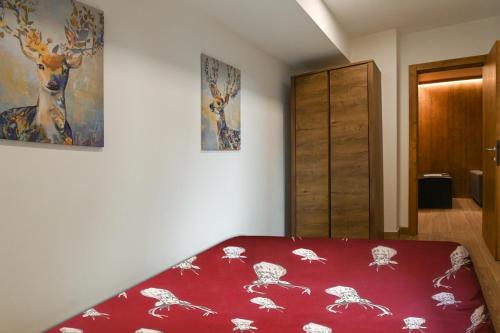 Un dormitorio con una cama roja con una foto de ciervo en la pared en Chalet 5 Laghi / LuxApt / Town Centre, en Madonna di Campiglio