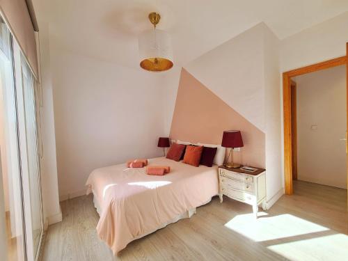a white bedroom with a bed and a night stand at Apartamento Cartagena centro in Cartagena
