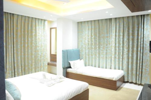 a room with two beds and a window with curtains at Hotel City Heart Shirdi in Shirdi