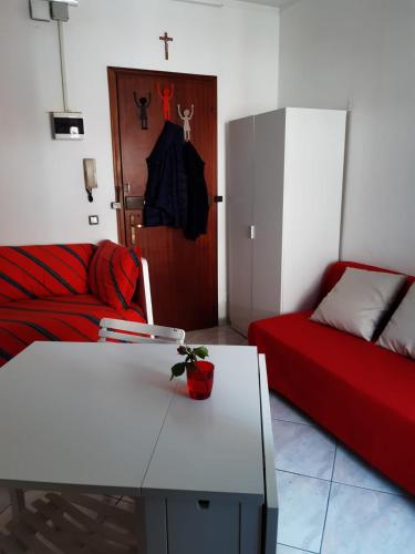 ein Wohnzimmer mit einem weißen Tisch und einem roten Sofa in der Unterkunft Aria in Porto Santa Margherita
