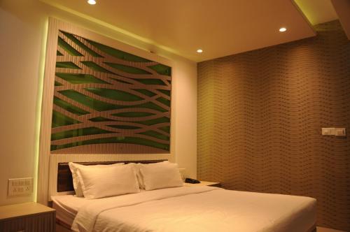 a bedroom with a bed and a painting on the wall at Hotel City Heart Shirdi in Shirdi