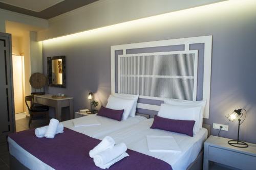 a bedroom with two beds with white sheets and purple pillows at Elia Potie in Chania Town