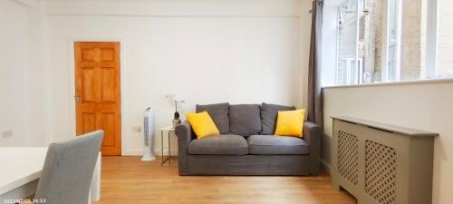 salon z szarą kanapą z żółtymi poduszkami w obiekcie Neptune Flat 9 at Marble Arch w Londynie