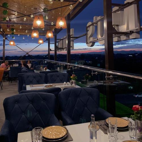 a restaurant with blue couches and a view of the city at Tomu's Hotel in Gyumri