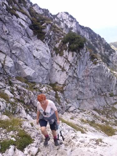 a woman is walking on a rocky mountain at B&B family room Tubej in Bohinj