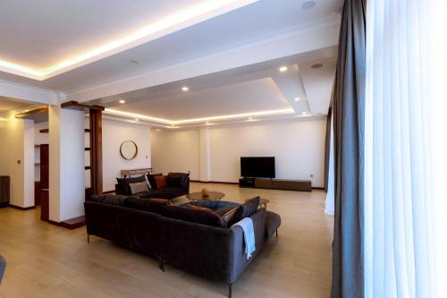 a living room with a couch and a tv at MAYA Residences Rwanda in Kigali