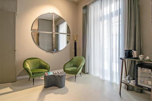a living room with two green chairs and a mirror at Atelier Inès Arts & Suites in Naples