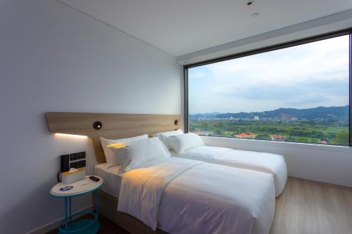 a hotel room with two beds and a large window at SOJO Hotel Lang Son in Lạng Sơn