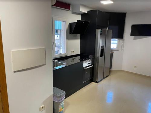 uma cozinha com um frigorífico de aço inoxidável e armários pretos em Estudio en Ribeira em Ribeira