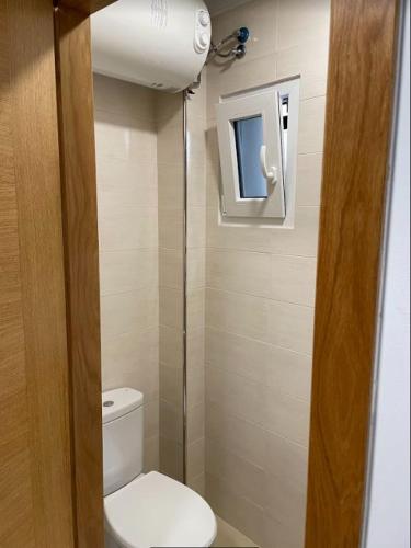 a small bathroom with a toilet and a window at Estudio en Ribeira in Ribeira