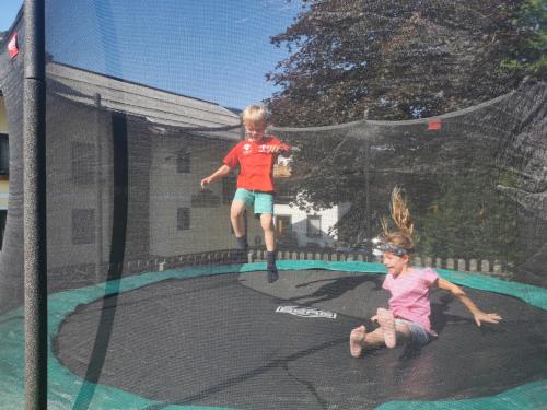 two children are playing on a trampoline at Hotelpension Oberauer Wagrain in Wagrain