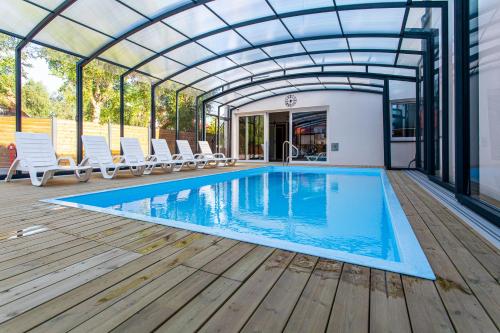 a swimming pool with a glass roof and a deck with chairs at Domki Premium LATO&ZIMA z basenem in Dębki