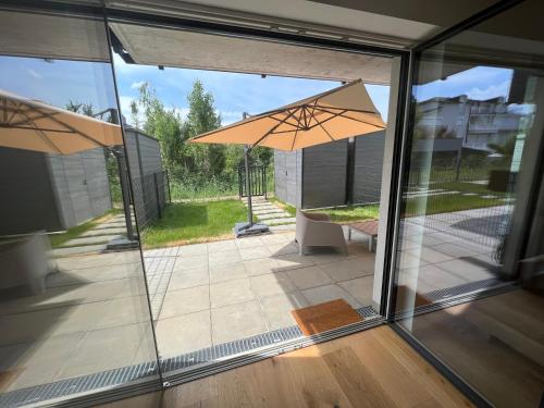 uma porta de vidro aberta com um pátio com um guarda-chuva em 25h SPA-Residenz BEST SLEEP privat Garden & POOLs em Neusiedl am See