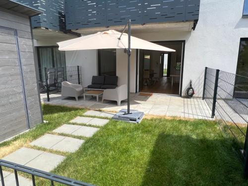 a patio with an umbrella and a table and chairs at 25h SPA-Residenz BEST SLEEP privat Garden & POOLs in Neusiedl am See