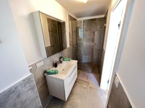 a bathroom with a white sink and a shower at 25h SPA-Residenz BEST SLEEP privat Garden & POOLs in Neusiedl am See