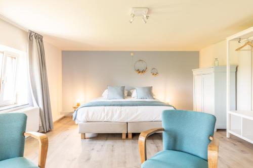 a bedroom with a bed and two blue chairs at Gîte Athois la campagne in Ath