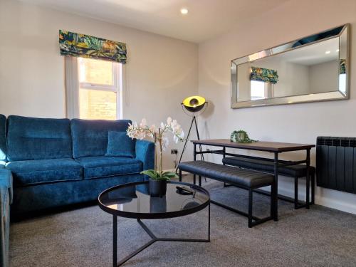 a living room with a blue couch and a mirror at DYSA Clifton Apartments in Lytham St Annes