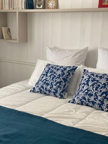 un lit avec des oreillers bleus et blancs dessus dans l'établissement Élégante maison de village au cœur de La Noue, à Sainte-Marie de Ré