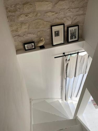 Un escalier blanc avec une fenêtre et des photos sur un mur dans l'établissement Élégante maison de village au cœur de La Noue, à Sainte-Marie de Ré