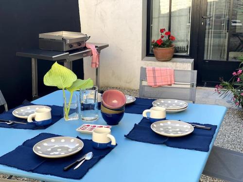 une table bleue avec des assiettes et des ustensiles dans l'établissement Élégante maison de village au cœur de La Noue, à Sainte-Marie de Ré