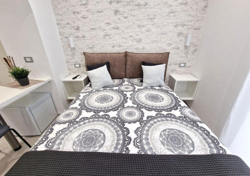 a bedroom with a bed with a black and white quilt at B&B Tra le vie del borgo in Vieste