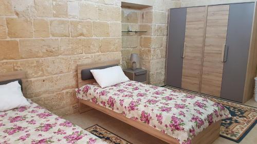1 dormitorio con 2 camas en una pared de piedra en Dar il-Hena, en Żurrieq