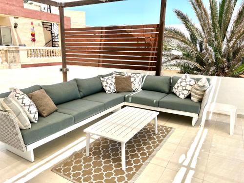 - un canapé vert et une table sur la terrasse dans l'établissement Villa Michael, à San Pawl il-Baħar