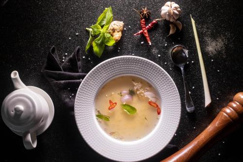 a bowl of soup on a table with vegetables and a teapot at Dahlia Boutique Hotel in Pokhara