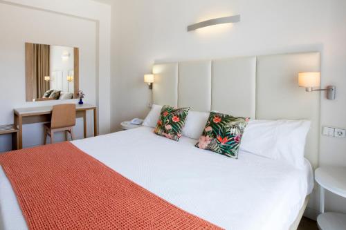 a bedroom with a large white bed with two pillows at Hotel Levante in Es Pujols