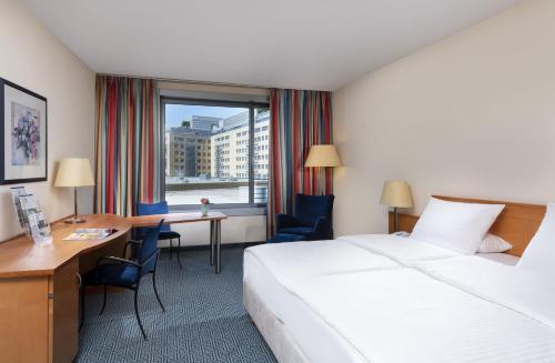 a hotel room with a bed and a desk and a window at Maritim Hotel Frankfurt in Frankfurt/Main