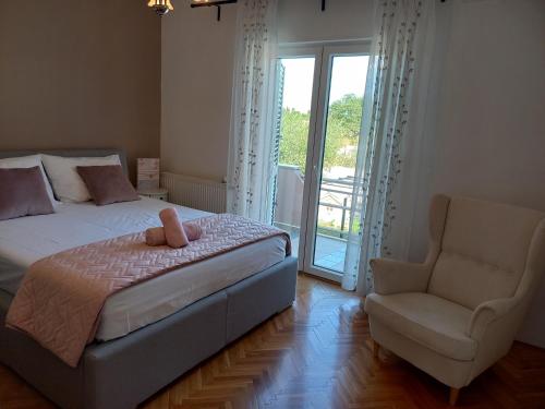a bedroom with a bed and a chair and a window at Villa Marta in Murvica