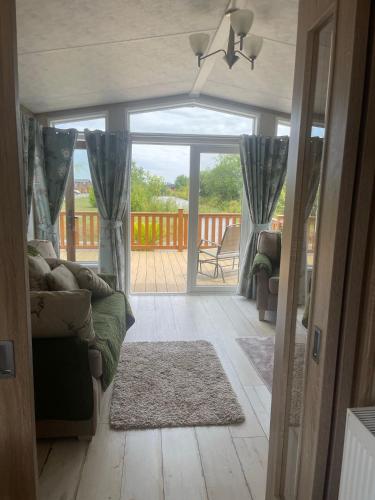a living room with a couch and a sliding glass door at Fern Lodge with Hot Tub in Stonham Aspall