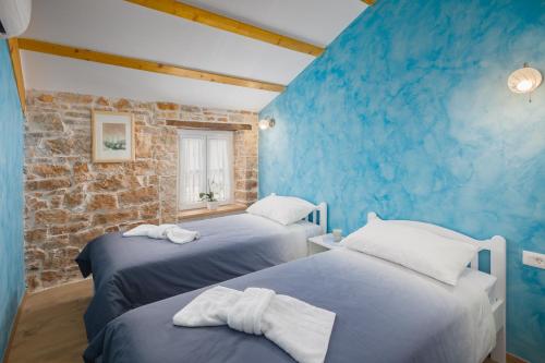 two beds in a room with a blue wall at Villa Ivea in Višnjan