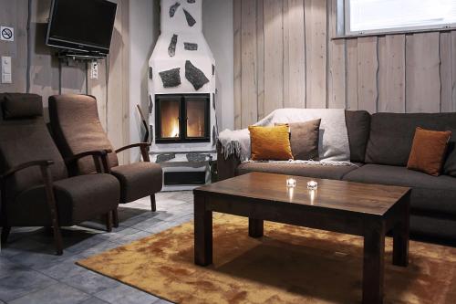 a living room filled with furniture and a fire place at Levin Alppitalot Alpine Chalets in Levi
