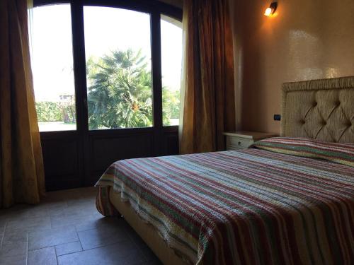 een slaapkamer met een bed en een raam met een palmboom bij Borgo dei Normanni in San Vito dei Normanni