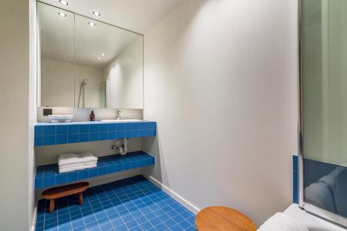 La salle de bains est pourvue de carrelage bleu et d'un miroir. dans l'établissement Subliem relax app 6p met buitenzwembad & tuin, à La Panne
