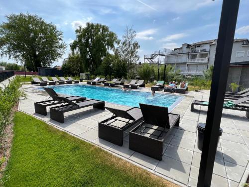 a swimming pool with lounge chairs next to a building at 25h SPA-Residenz POOLs IN & OUT, private Garden & Beach in Neusiedl am See