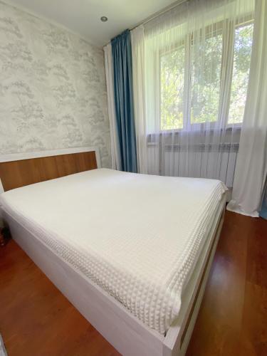 białe łóżko w pokoju z oknem w obiekcie Апартаменты аэропорт w mieście Ałma-Ata