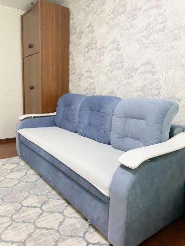 a bed with blue pillows on it in a room at Апартаменты аэропорт in Almaty
