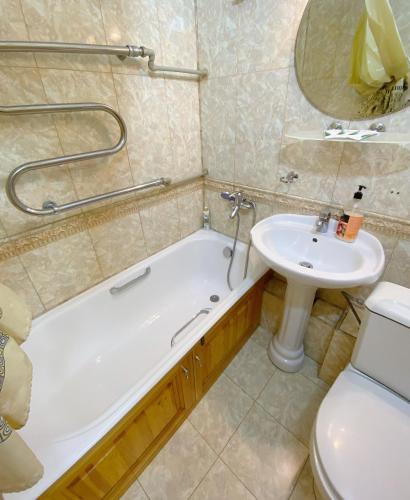 a bathroom with a tub and a sink and a toilet at Апартаменты аэропорт in Almaty