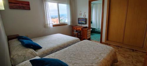pokój hotelowy z dwoma łóżkami i telewizorem w obiekcie Pisos Vistalegre 2B con jardín cerca del mar w mieście Sanxenxo